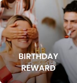A person surprises another with a birthday cake and candles while playfully covering their eyes.